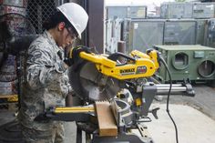 a man in camouflage is using a machine to cut wood with a circular sawtoother