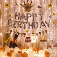 a happy birthday banner with balloons and confetti in front of white curtained backdrop