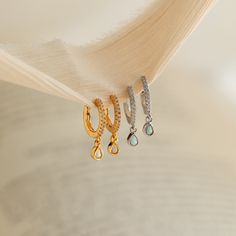 Introducing our Opal Drop Earrings, a stunning combination of sophistication and natural beauty. These earrings are crafted with diamond studs alongside the Huggie Hoops and with a vibrant opal gemstone that delicately dangle, adding a touch of elegance and enchantment to any outfit! ♡ Material: High Quality Solid 925 Sterling Silver Finish: Sterling Silver ∙ 18K Gold Hoop Dimensions: ~12mm Outer Diameter | ~7mm Inner Diameter Featuring Pave CZ Diamond Hoop Earrings with ~4.5mm x ~3mm Opal Drop Aquamarine Stacking Ring, Opal Drop Earrings, Duo Beads, Pearl Anklet, Diamond Huggies, Beaded Anklets, Chain Anklet, Diamond Hoop Earrings, Cz Diamond