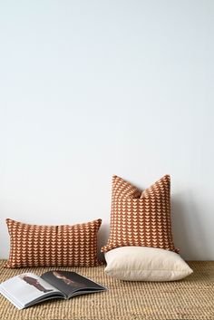 two pillows sitting on top of a bed next to an open book