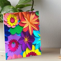 colorful paper flowers on a table next to a potted green plant art board print