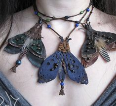 a close up of a woman wearing a necklace with several different colored moths on it