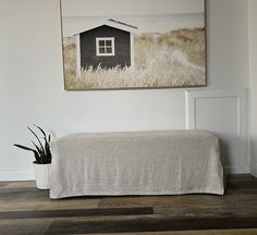 a room with a bed and a painting hanging on the wall next to a potted plant