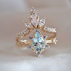 an engagement ring with blue and white stones on it, sitting on top of a piece of cloth