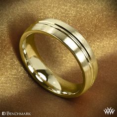 a gold wedding ring with two lines on the inside of it, sitting on a brown cloth