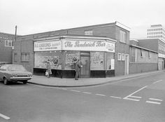 an old black and white photo of a man standing in front of a barbershop