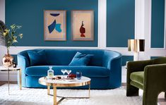 a living room with blue couches and paintings on the wall above them, along with a coffee table