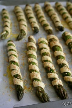 asparagus wrapped in cheese and herbs on a baking sheet