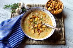 a bowl of soup on a place mat next to two bowls of food