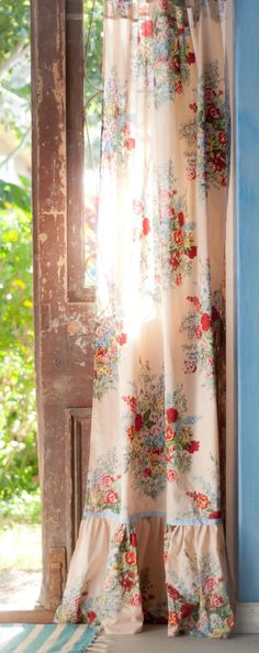 an open window with curtains and flowers on it