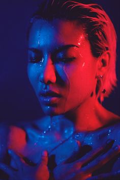 a woman with her face covered in blue and red light, holding her hands together