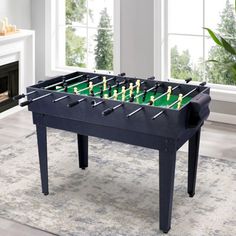 a foosball table in the middle of a living room with a fireplace and large windows