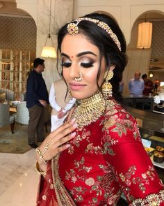 a woman in a red dress with gold jewelry on her head and nose is looking at the camera