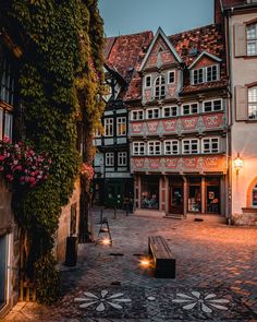 a cobblestone street in an old european town at night with flowers on the windows