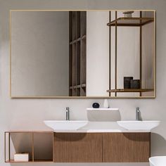 a bathroom vanity with two sinks and a large mirror above it, in front of a white wall