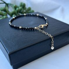 You just can't have too much black in your wardrobe - or your accessories!  Check out this gorgeous, sparkly Black Zircon and Gold Bead Bracelet with a 14K gold-filled adjustable chain that includes a quality stamped heart tag. The bracelet adds just the right amount of sparkle to any outfit. It is dainty and feminine and perfect to wear solo or for stacking with our other bead bracelets.. Waterproof and tarnish resistant!  Adjustable Clasp: Whether you have a tiny wrist or need a bit more room, Faceted Black Crystal Bracelet Gift, Adjustable Black Crystal Bracelet For Party, Elegant Gold Bracelets With Black Beads, Black Bracelet With Gold Beads, Black Crystal Bracelet With Faceted Beads For Party, Adjustable Black Faceted Jewelry, Black Crystal Bracelet With Round Beads For Party, Black Faceted Beads Crystal Bracelet For Party, Black Faceted Jewelry For Party