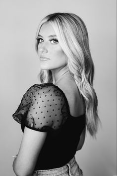 a woman with long blonde hair posing for a black and white photo wearing a sheer top