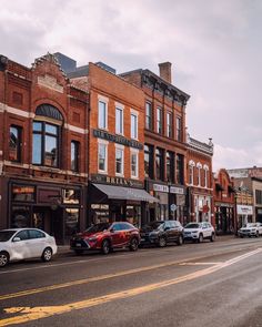 cars are parked on the side of the road in front of shops and businesses,