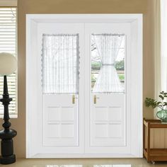 two white double doors with sheer curtains on the windowsills in front of them