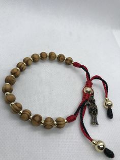 "Pulsera de madera natural 8mm cafe y bolas de oro laminado 4mm y 8mm dorado decorado en un dije de la Santa Muerte en metal dorado rustico, Ajustable y expandible para hombre o mujer hecho a mano con hilo de Nylon reforzado color negro y rojo #18, con un cierre minimo desde 7\" pulgadas y ajustable hasta 9\" pulgadas" Natural Wood Jewelry With 8mm Beads, Spiritual Gold Bracelets With Wooden Beads, Spiritual Gold Bracelet With Wooden Beads, Gold Bracelets With Wooden Round Beads, Handmade Gold Wooden Jewelry, Handmade Wooden Gold Jewelry, Slide Lock, Sliding Knot, Black Bracelets