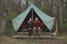 a man and woman sitting in front of a tent