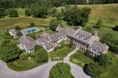 an aerial view of a large house with a pool in the center and trees surrounding it