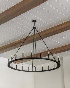 a chandelier hanging from the ceiling in a room with white walls and wood beams