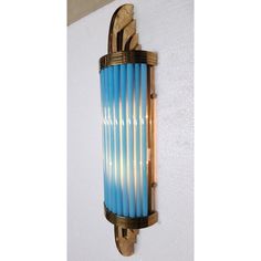 a blue light fixture mounted to the side of a wall next to a white wall