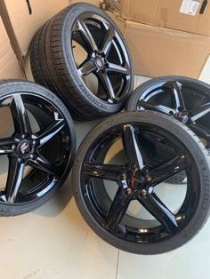 four black rims and tires are sitting on the floor