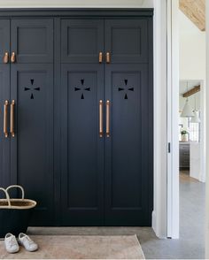 a pair of shoes sitting on the floor in front of a black cabinet with brass handles