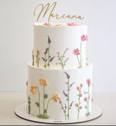 a three tiered cake decorated with flowers and the word merana on it's side