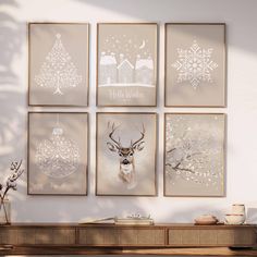 four christmas cards hanging on the wall in front of a table with a vase and potted plant