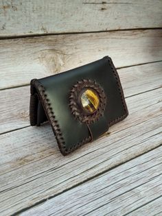 "This is your small genuine leather wallet! A unique quality gift for her! Made carefully by quality calf leather that it ages beautifully gaining shine by the time! This wallet is totally handcrafted in my studio with a quality Tiger Eye gem stone. As you can observe at the fotos this bilfold is hand stitched with leather string; this makes it stronger and durable!  It features 5 credit card slots that can hold 3-4 cards each, as well as a spacious cash slot of 15cm for your notes!  Also, as you can appreciate in the photos , it has enough space for your coins. The way i designed this outside coin's purse, makes it very spacious and easy to use! If you like this wallet but you need it a little bit different...longer or shorter..for example.. Just get in touch! I will be here to respond yo Handmade Leather Artisan Card Holder, Handmade Leather Card Holder Artisan Style, Handmade Artisan Leather Card Holder, Artisan Hand-stitched Wallet As Gift, Artisan Wallets With Coin Pocket, Artisan Rectangular Card Holder As Gift, Artisan Rectangular Card Holder Gift, Brown Hand-stitched Card Holder For Gift, Artisan Handmade Card Holder For Gifts