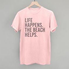 Life Happens. The Beach Helps. Pink Graphic Print T-shirt For Holiday, Beach Season Graphic Tee With Text Print, Graphic Tee With Text Print For Beach Season, Fun Beach Season T-shirt With Text Print, Letter Print T-shirt For Beach Season Holiday, Beach Holiday Graphic Print T-shirt, Beach Holiday Cotton T-shirt, Beach Season Holiday Cotton T-shirt, Graphic Print T-shirt For Beach Holiday