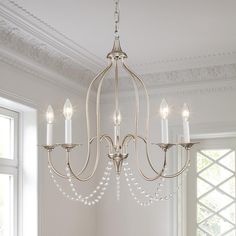 a chandelier hanging from the ceiling in a room with white walls and windows