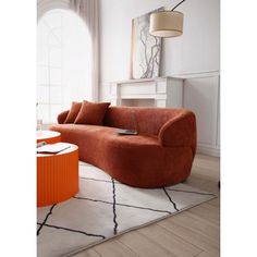 a living room with an orange couch and coffee table in front of a window on top of a rug