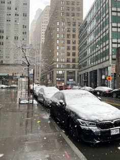 cars covered in snow parked on the side of a city street next to tall buildings