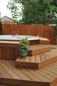 a hot tub sitting on top of a wooden deck next to a flower planter