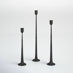 three tall black candlesticks sitting next to each other