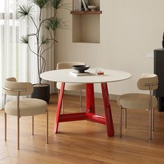 a white table and chairs in a room with wood flooring next to a window