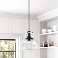 a light hanging from a kitchen ceiling over a table with plates and bowls on it