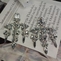 two crystal cross brooches sitting on top of a piece of paper next to each other