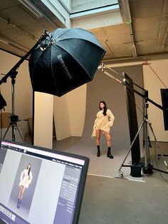 a woman is standing in front of a camera with an umbrella over her head,