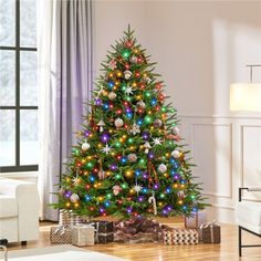 a brightly lit christmas tree in a living room with presents on the floor next to it