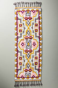 a multicolored rug with tassels hanging on the wall