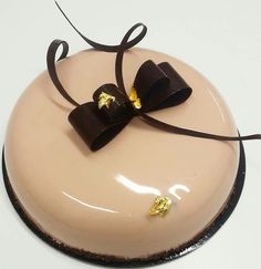 there is a chocolate cake with gold decorations on the top and black ribbon around it