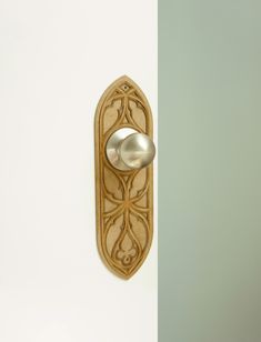 a spoon is hanging on the wall next to a doorknob with an ornate design