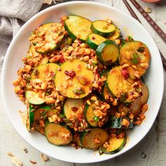 a white bowl filled with sliced cucumbers and other food on top of a table