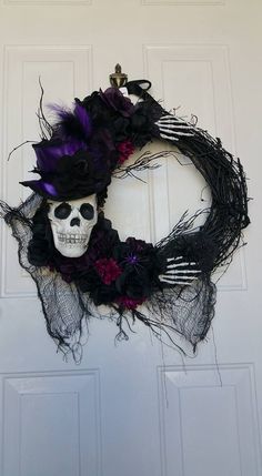 a wreath with a skull on it and purple flowers hanging from the side of a door