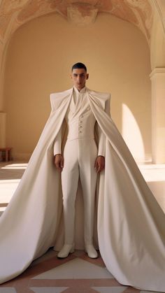 a man in a white suit and cape standing on the floor with his hands on his hips